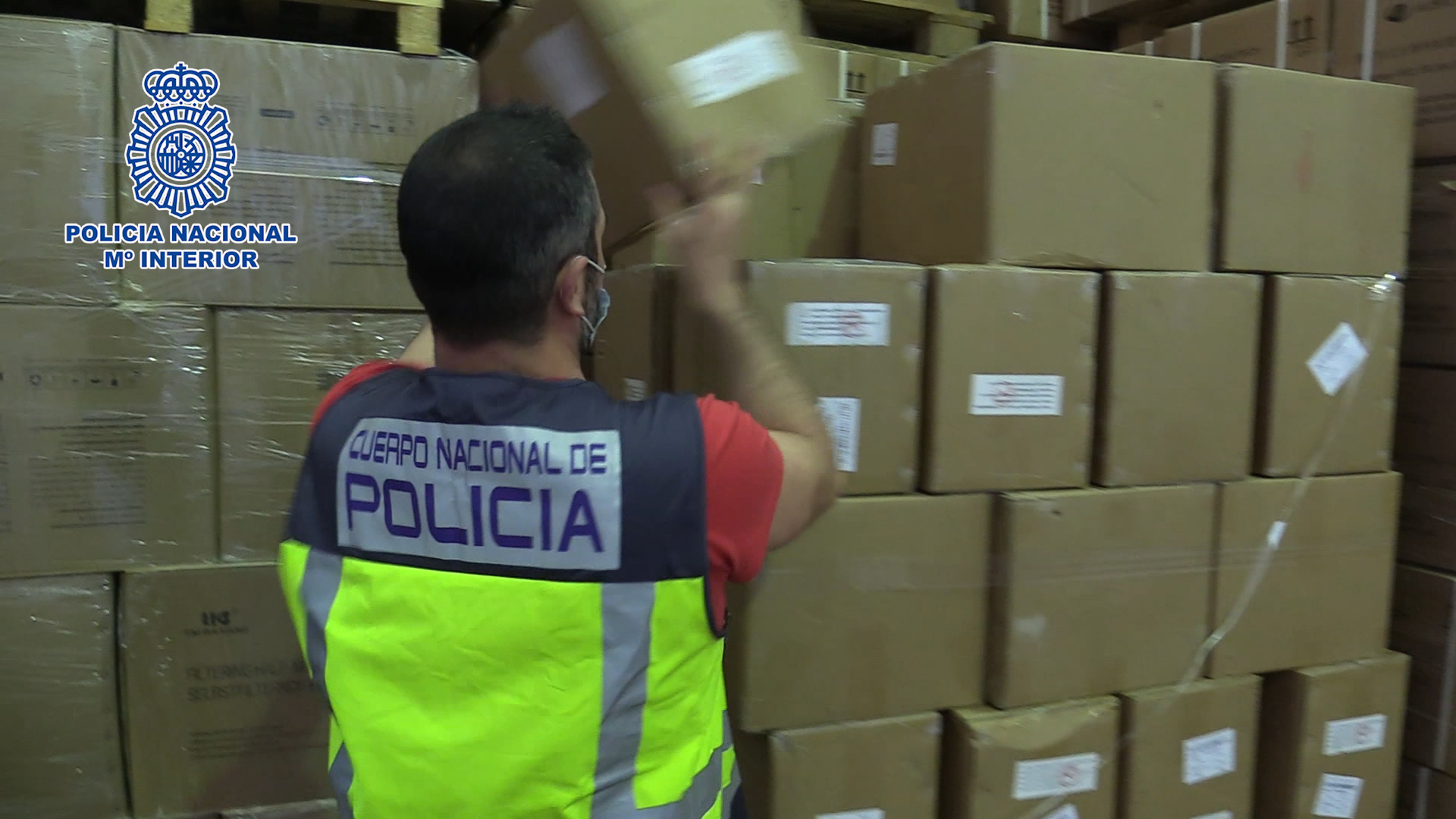 Un agent de Policia Nacional manipulant una caixa de cartó contenint test d'antígens requisats